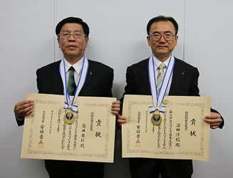 内閣総理大臣官邸にて行われた表彰式の写真。受賞者：沼田担当部長（右）と筒井部長（左）